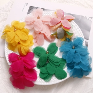 Detailed view of colorful multi-layered mesh puff flower charms with beads in a porcelain dish