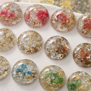 Macro detail of resin cabochons with gold foil and dried flowers for jewelry making