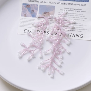 Detail of pink and white beaded tassel earrings with a botanical coral design on a tray