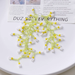 Handmade beaded necklace featuring light green and yellow beads with white flower charms