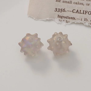 Macro view of iridescent matte acrylic sea urchin beads with center holes for DIY jewelry