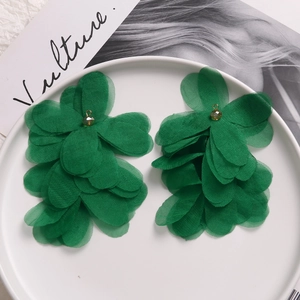 Detailed macro view of deep green multi-layered organza flower earrings on ceramic plate