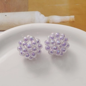 Detailed view of iridescent colorful acrylic bead cluster earrings on ceramic plate