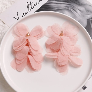 Detailed view of handmade pink organza layered puff flower earrings on white tray