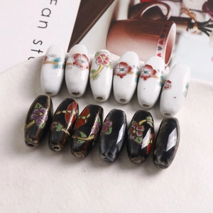 Detail von handbemalten ovalen Keramikperlen mit Blumenmuster für DIY-Schmuck in Schale