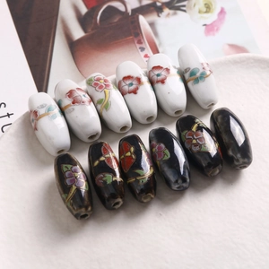 Makroaufnahme von ovalen Keramikperlen mit handgemalten Blumenmustern für DIY-Schmuck