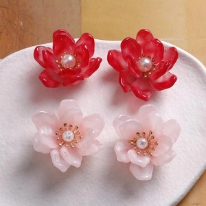 Vista detallada de aretes de flores de resina con perlas y estambres dorados finos