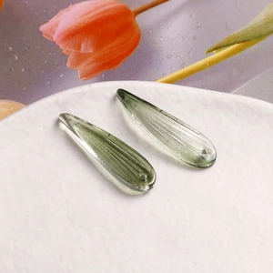 Détail de pendentifs gouttes en verre vert clair avec rayures pour création de bijoux DIY