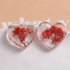 Detailed close-up of heart-shaped resin charms with red dried flowers and white pearls
