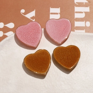 Detailed view of pink and gold glitter heart resin charms on a textured ceramic plate