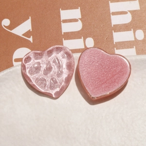 Macro shot of glittery heart-shaped resin charms with textured hammer and smooth finishes