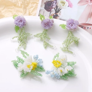 Detailed close-up of handmade beaded wisteria and flower clusters in a white ceramic dish