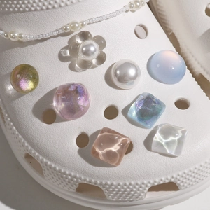 Detailed view of iridescent pearl charms and aurora crystal beads on white clogs shoes