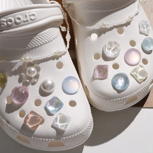 Detail of colorful resin shoe charms with faux pearls on white clogs for DIY style