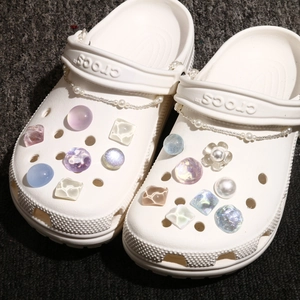 Close-up of DIY pearl chains and glittery candy-colored charms on white garden clogs
