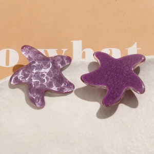 Vue macro de breloques étoile de mer en résine violette avec paillettes et texture ondulée