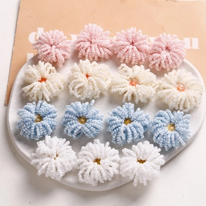 Dettaglio di fiori di perline fatti a mano nei colori rosa, blu, giallo e bianco