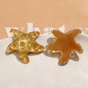Vue macro de breloques étoiles de mer en résine pailletée aux textures dorées