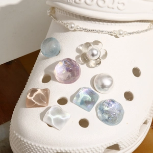 Macro detail of glitter water ripple shoe charms and elegant faux pearl chain set