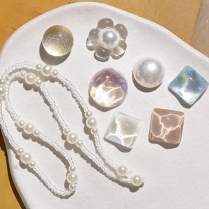 Macro detail of iridescent crystal gems and pearl charms for DIY shoe decoration