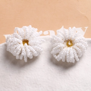 Dettaglio di fiori di perline bianche fatti a mano con centro giallo per gioielli fai-da-te