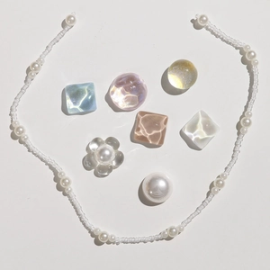 Detailed flat lay of iridescent crystal shoe charms and colorful pearls for DIY clogs