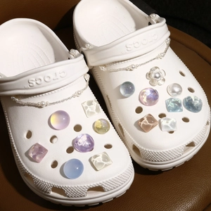 Detailed view of DIY pearlescent charms and shimmering resin gems on white garden clogs