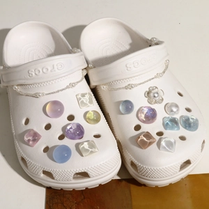 Detailed view of DIY charms on white clogs featuring pearl chains and resin beads