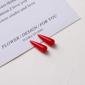 Detail shot of glossy red resin drop charms on a white decorative card for DIY earrings