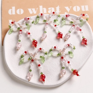 Detail of five handmade pearl bow charms with green leaves and cherry fruit pendants