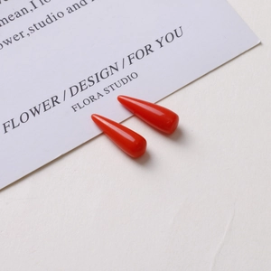 Detail view of two shiny red resin cone pendants for DIY jewelry making accessories