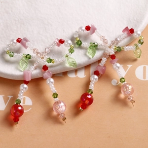 Beaded bow earrings with white pearls, green leaves, and pink crystal accents