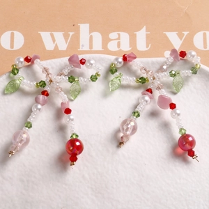 Macro shot of handmade bow charms with pearls, green leaf beads and red tassels