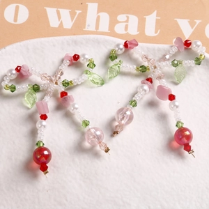 Close-up of colorful butterfly bow earrings with pearls and green leaf beads