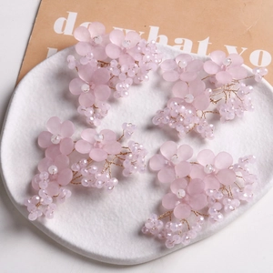 Detailansicht von rosa mattierten Blumenhaarschmuck mit lila Perlen auf einem Tablett
