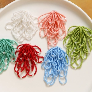 Close-up of handmade beaded flower tassels for jewelry making in six pastel colors