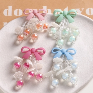 Macro view of macaron resin bow and iridescent cherry beads charms in four pastel colors