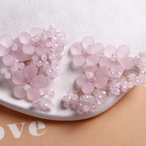 Makroaufnahme von handgefertigtem Blumenschmuck mit rosa Blüten, lila Perlen und Golddraht