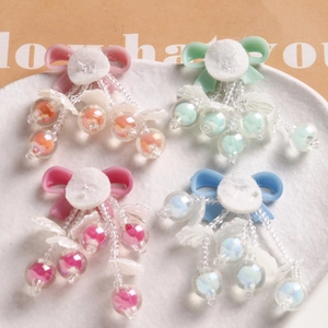 Detail of handmade bow charms with beaded tassels in pastel pink, green, and blue tones