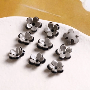 Macro view of grey five-petal resin flower beads on a white ceramic tray for DIY jewelry