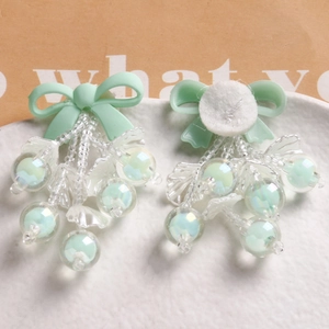 Detail of handmade light green bow accessories with transparent beaded pendants on tray