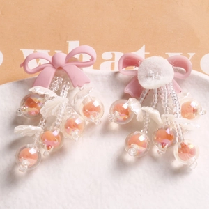 Detailed view of handmade pink bow earrings with iridescent glass beads on ceramic plate