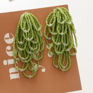 Detailed view of handmade grass green beaded tassel earrings with crystal bead accents
