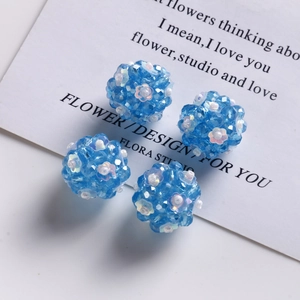 Detailed view of four blue faceted glass bead spheres with tiny white flower accents