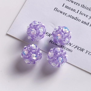 Detailed view of four handmade purple beaded floral spheres for DIY jewelry making
