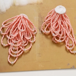 Elegant pink bead flower earrings with crystal tassels on a natural textured background