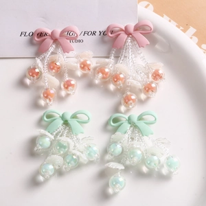 Pink and mint green bowknot beaded tassel earrings on a white decorative plate