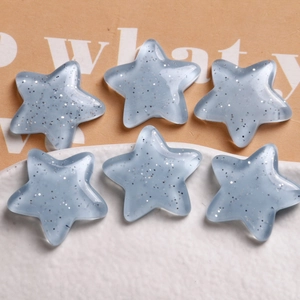 Macro detail of light blue resin star pendants with silver glitter for DIY jewelry