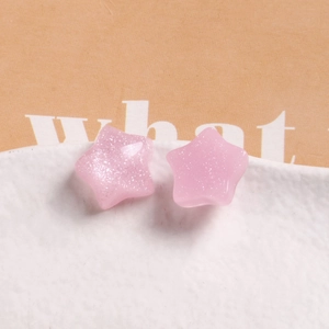 Detail of pink jelly pentagram charms with silver glitter on white textured porcelain