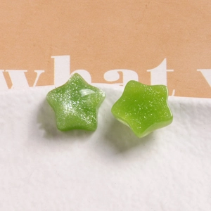 Macro view of green translucent star-shaped DIY charms with sparkling silver glitter